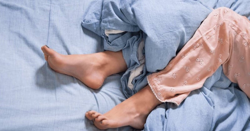 Image de pieds sous les couvertures dans un lit