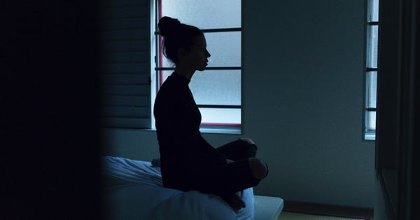 Woman sitting on her bed at night